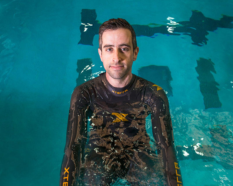 Man swimming in a wet suit in a pool.